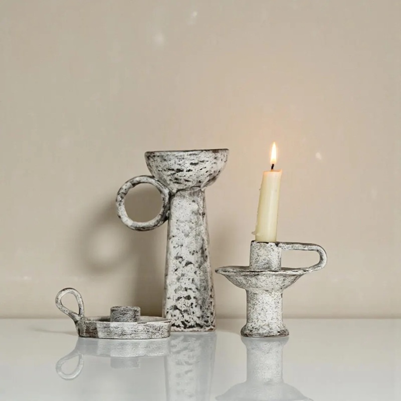 Three sizes (small/medium/large) of vintage distressed ceramic handle candle holders displayed together, with a lit candle on the medium one